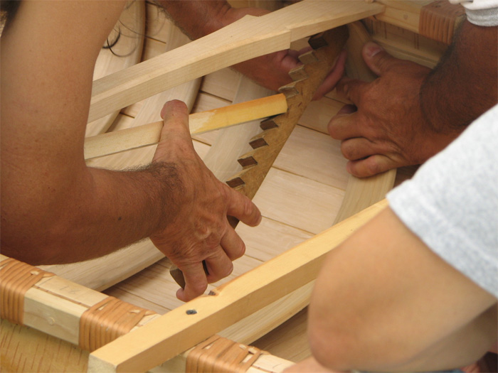 The "rib spreader" being used to insert the rib ends under the inwales, and to form the tumblehome in the sides